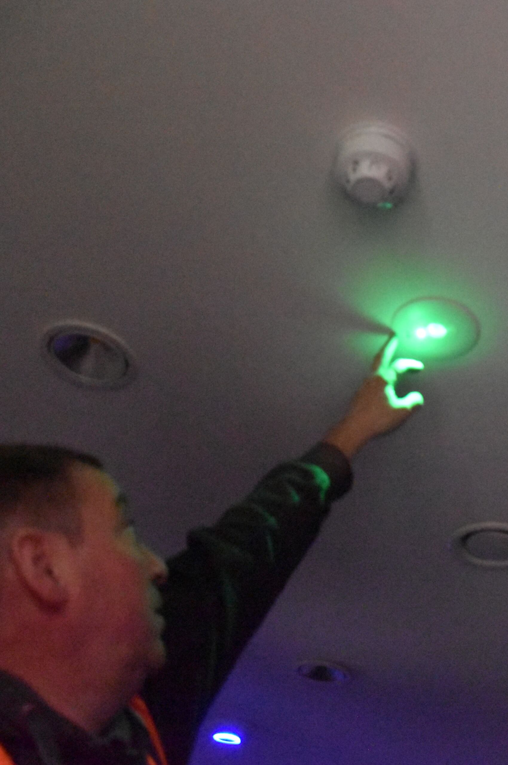 Engineer testing a ceiling LED downlight during lighting upgrade commissioning