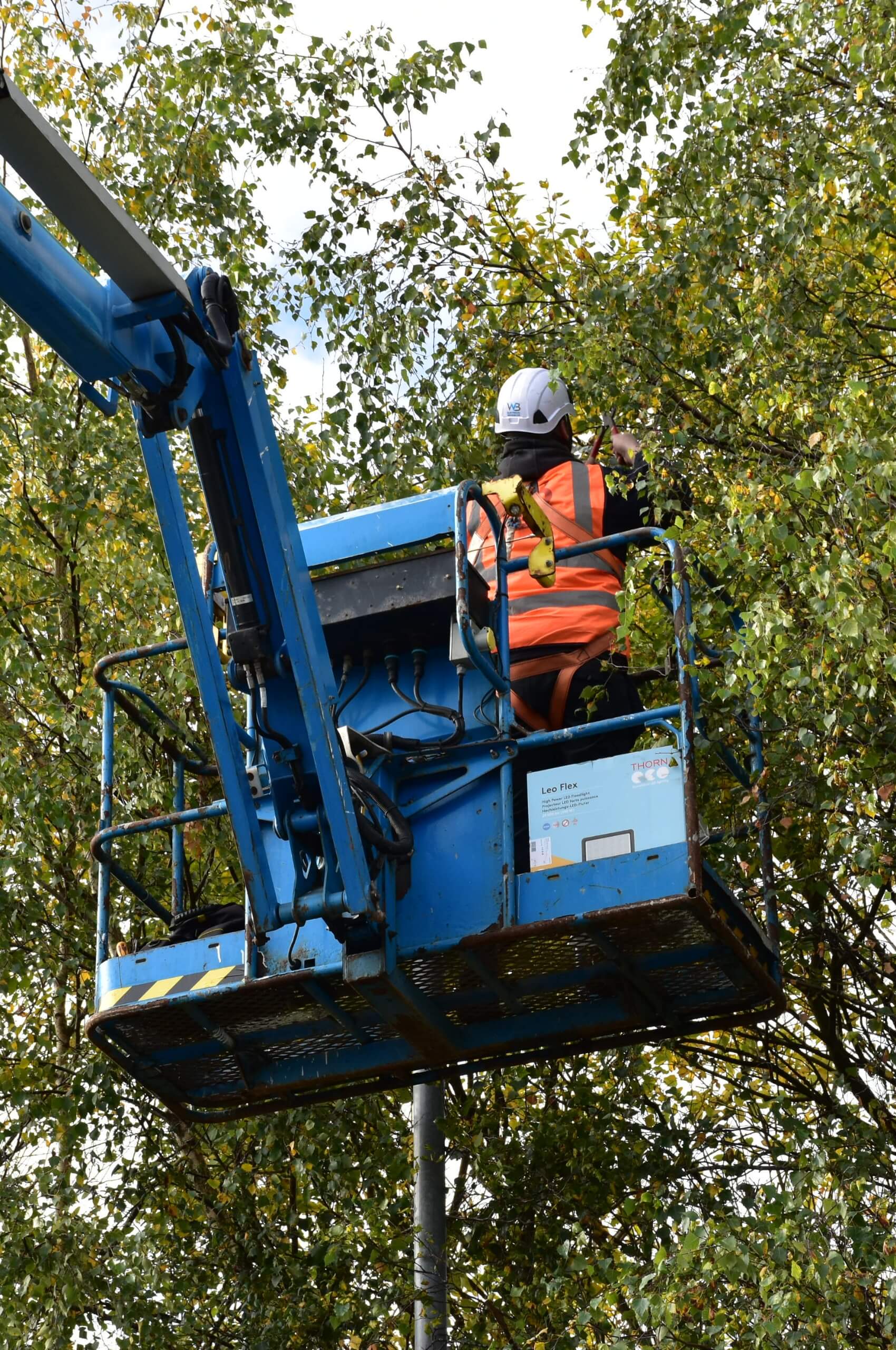 Engineer servicing high level lighting from cherry picker during maintenance inspection