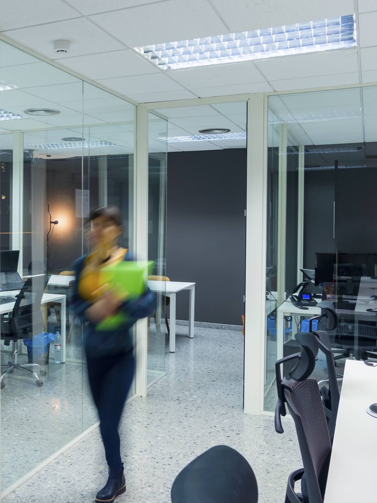 Occupied office with glazed rooms, workstations and ceiling lighting